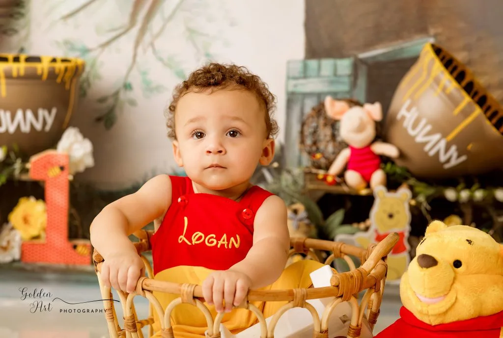 Baby in a red outfit sitting in a basket in a woodland birthday setup